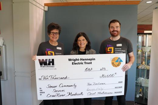 Three people hold up a big check given to them by Wright-Hennepin Electric