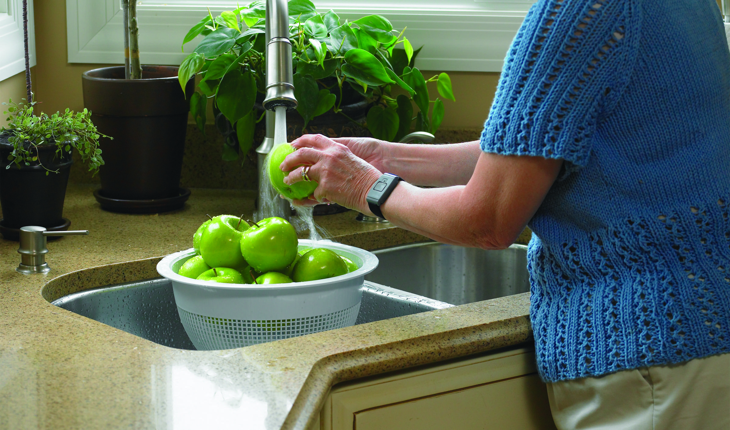 Elder woman cleans apple in sink