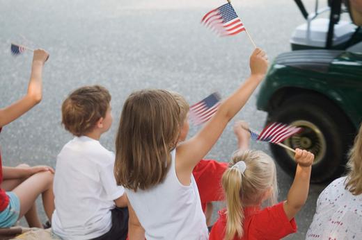 Kids wave American flags at a parade