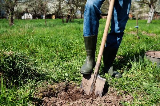 A man in boots digging up the ground