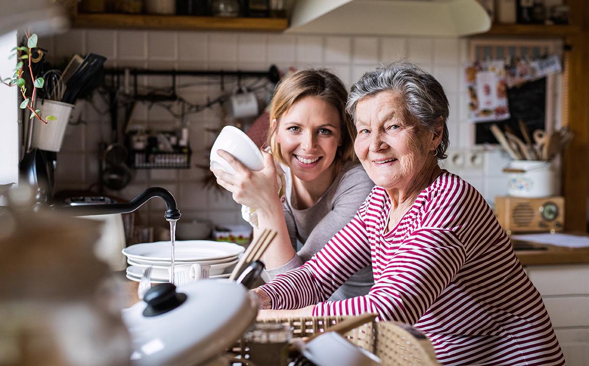 Elder woman cleans apple in sink