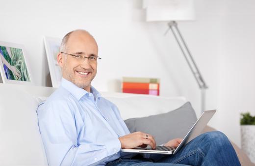 A man adjusting his thermostat and smiling because of the energy he is now saving