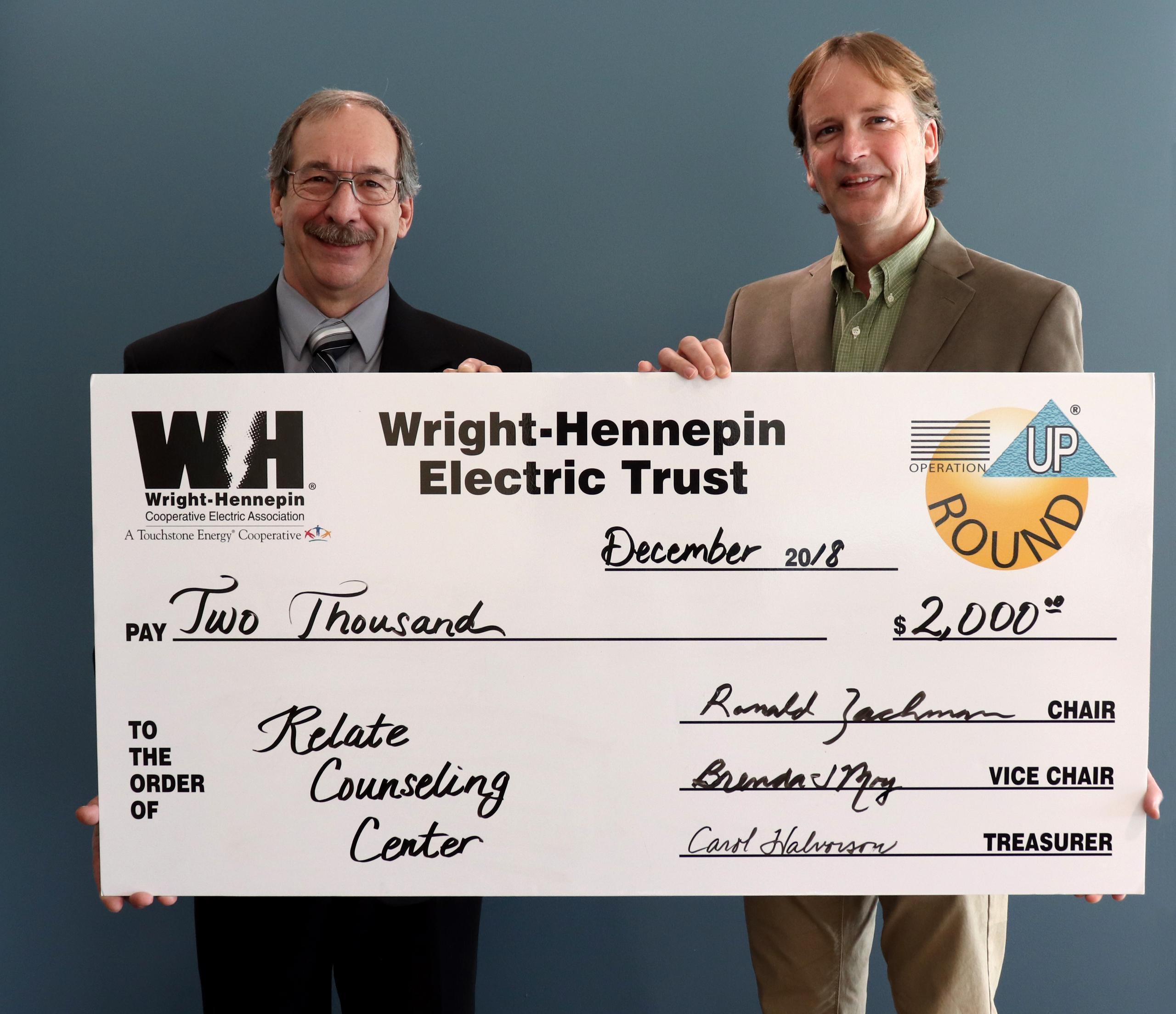 Two people hold up check given to them by Wright-Hennepin Electric