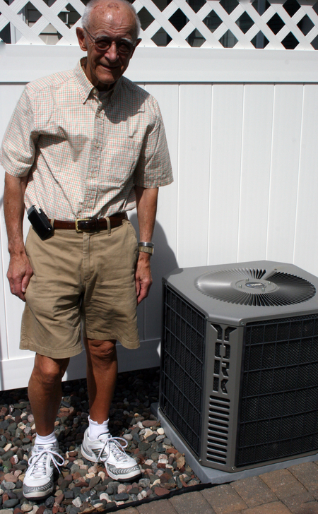 Wright-Hennepin Electric member stands next to his air conditioner