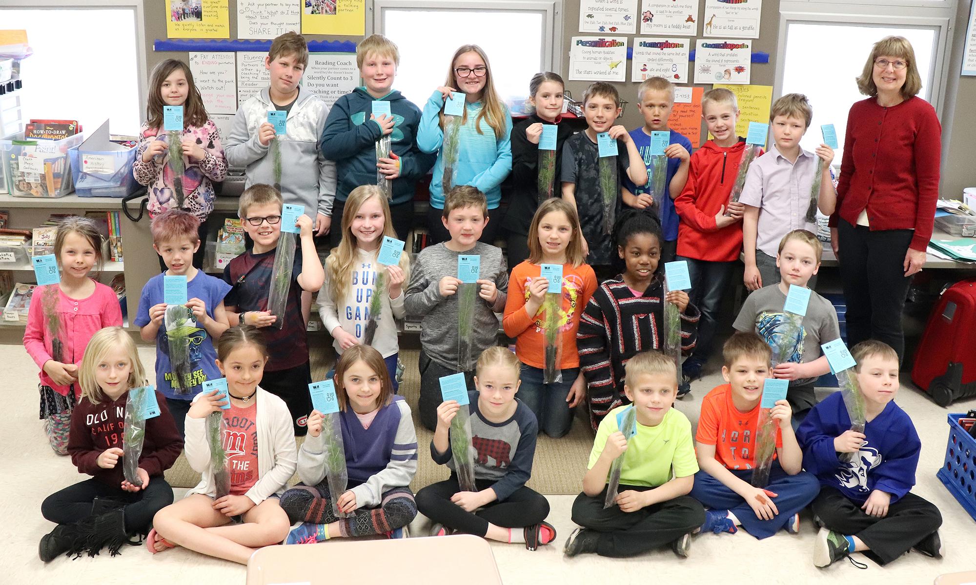 A classroom of students from Northwinds Elementary School in Buffalo hold up their new tree seedlings