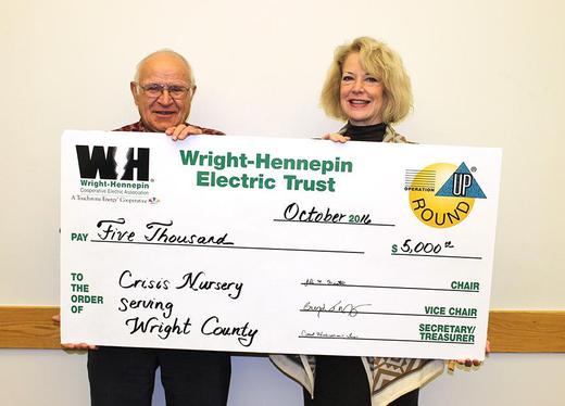 Two people hold up check given to them by Wright-Hennepin Electric