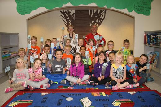 A classroom of students hold up their new tree seedlings