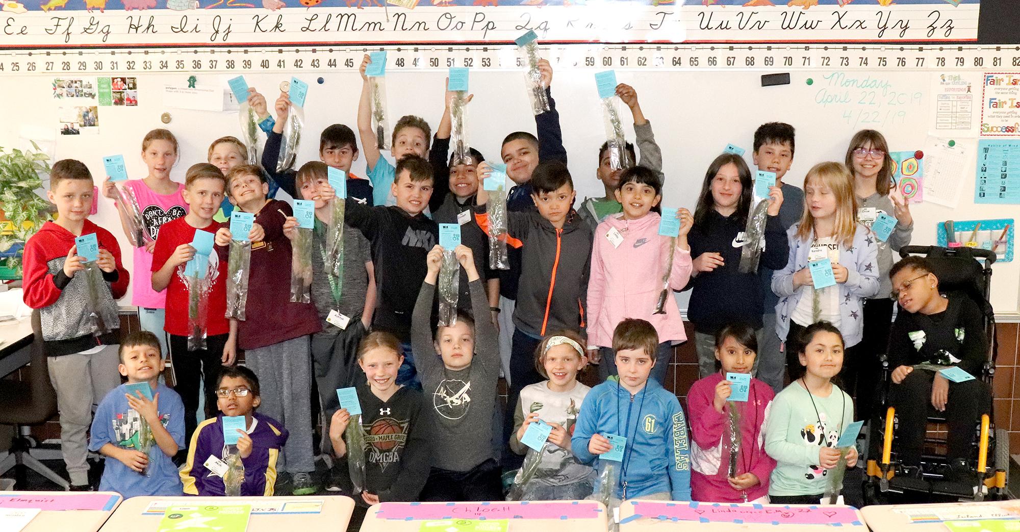 A classroom of students from Northwinds Elementary School in Buffalo hold up their new tree seedlings
